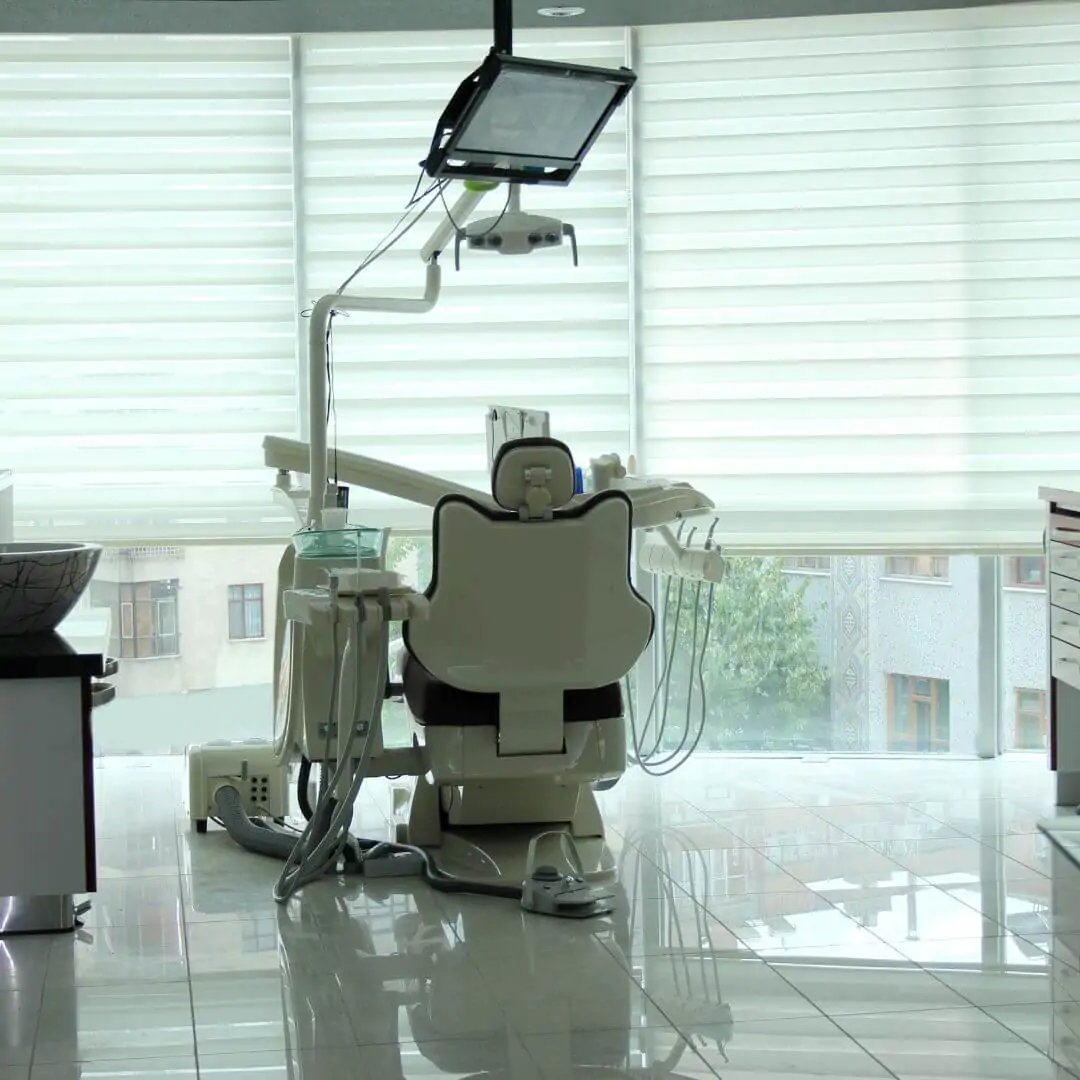 View of a sanitized white dental chair from the back, overlooking a clean window in a modern medical office.